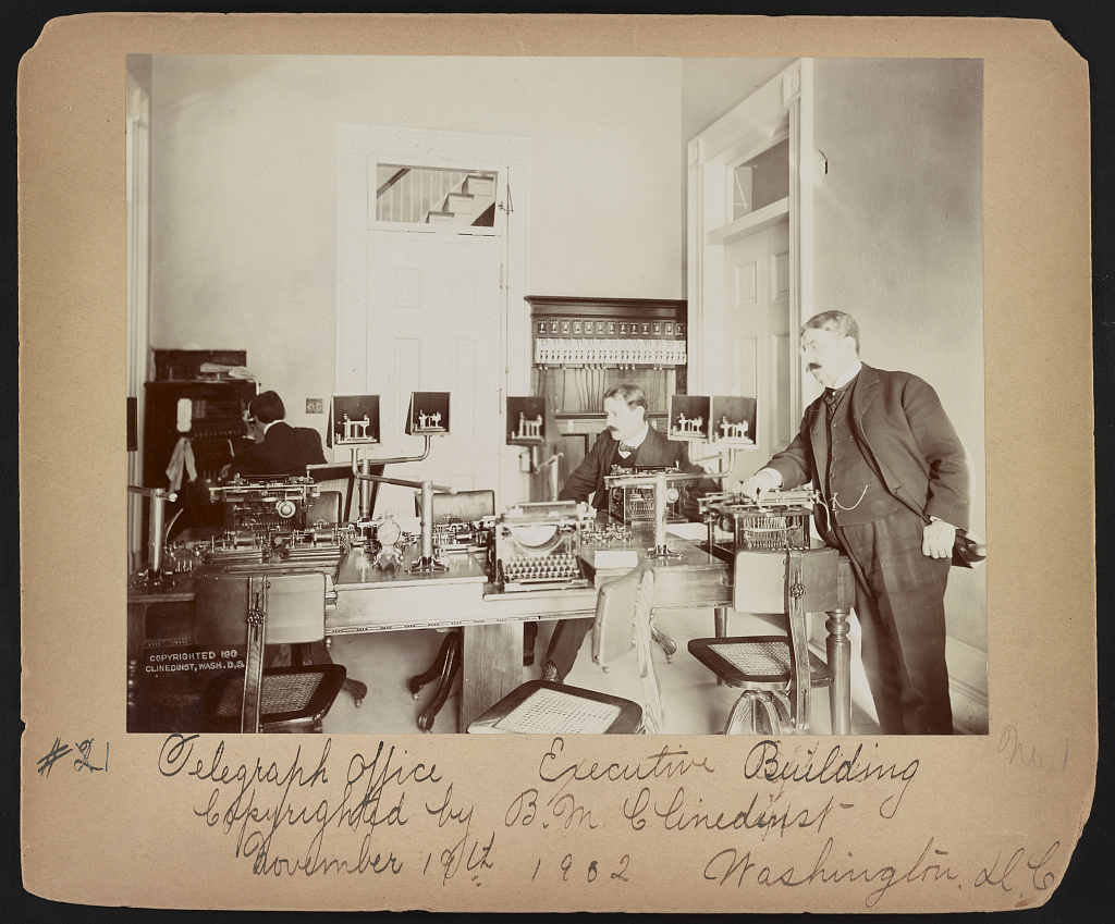 Public domain photograph of a telegraph office interior with desks, wires, and communications equipment.